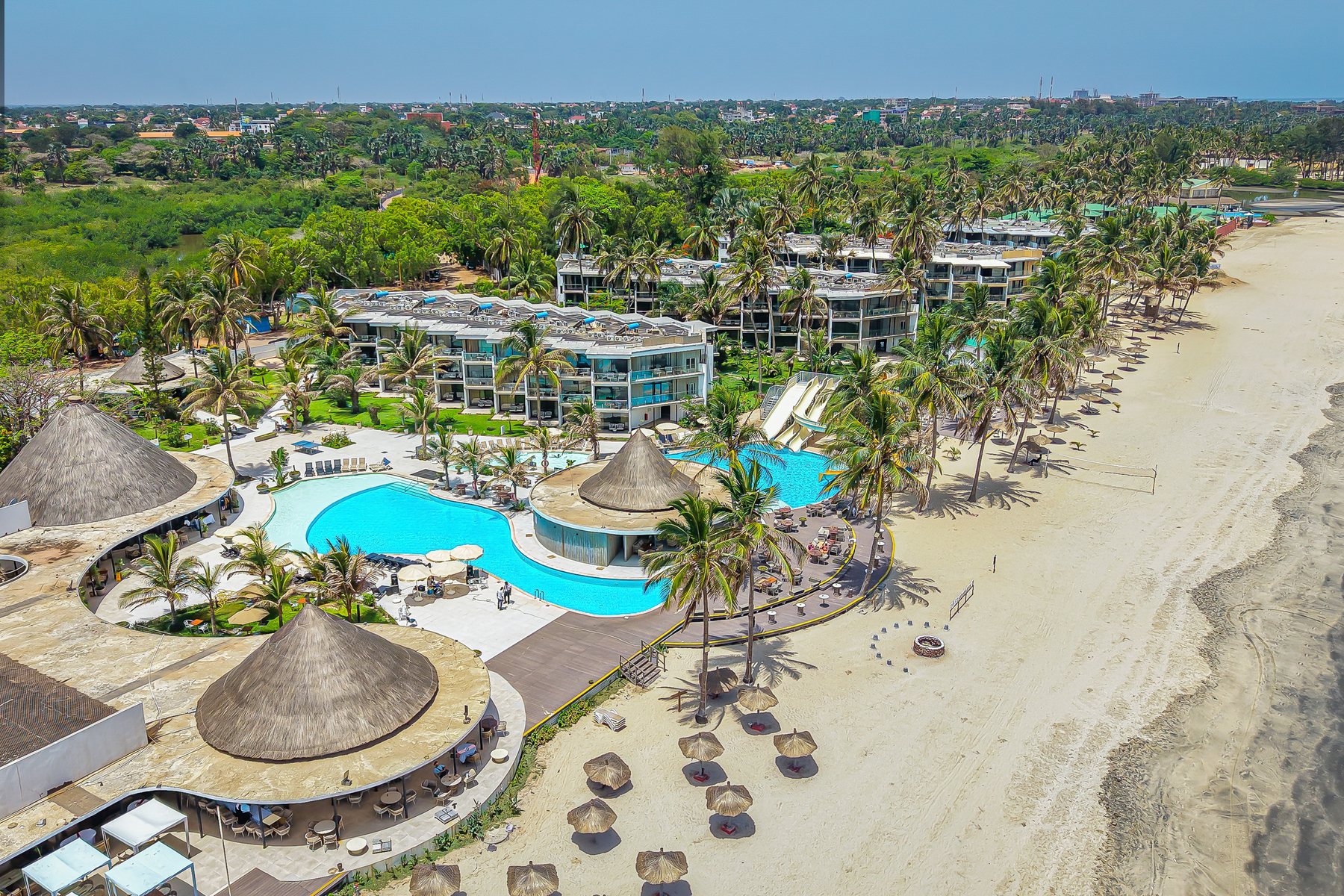 Aerial view of Kombo Beach Resort beside Kotu Beach, with pools, palm trees and the Atlantic shoreline